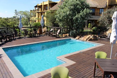 比勒陀利亚Ndlovu Lodge的庭院中一个带椅子和桌子的游泳池