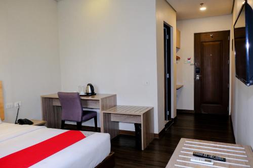 马尼拉Airo Hotel Manila的配有一张床和一张书桌的酒店客房