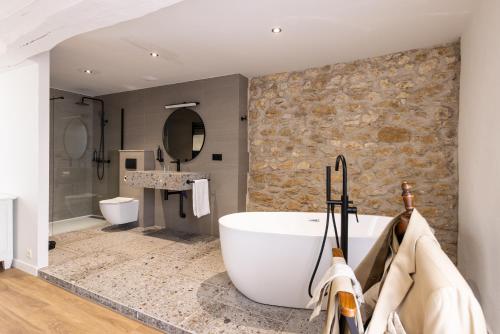 圣日的贡桑斯城堡酒店的一间带大浴缸和石墙的浴室