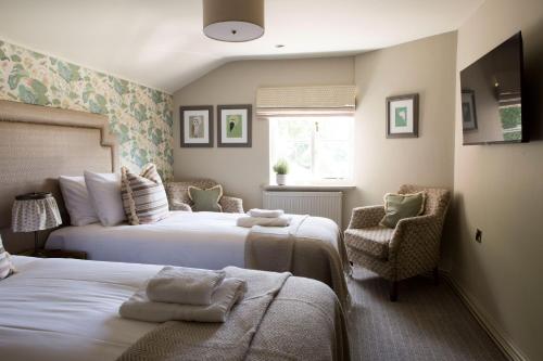 塔博雷Alvanley Arms, Cotebrook的一间卧室配有两张床和椅子