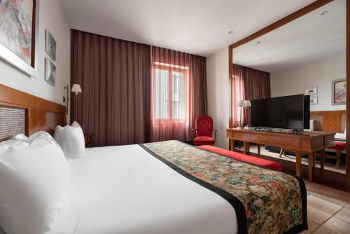 普拉森西亚阿方索八世EXE酒店的酒店客房设有一张大床和一张书桌。