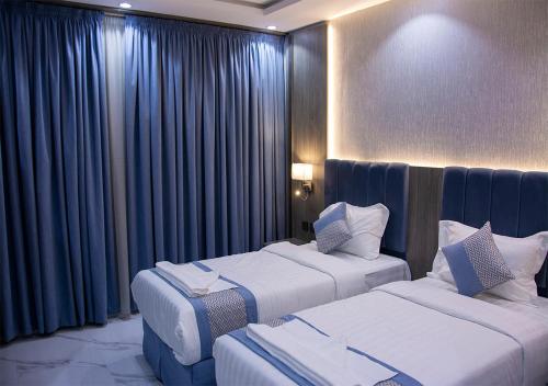 麦地那اجنحه البيداء فرع البخاري2的两张位于酒店客房的床,配有蓝色窗帘