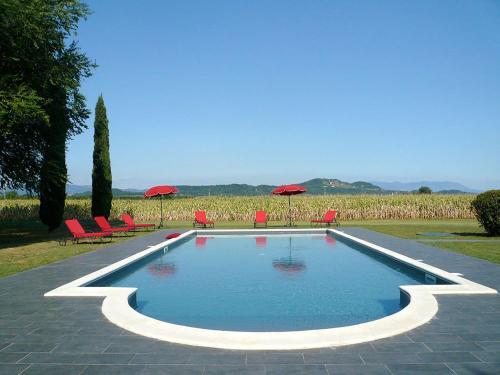 San Giovanni al Natisone博瑞迪卡瓦迪普乡村民宿的一个带红色椅子和遮阳伞的游泳池