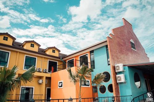 武里南Tuscany Hotel Buriram的前面一排种有棕榈树的五彩缤纷的建筑