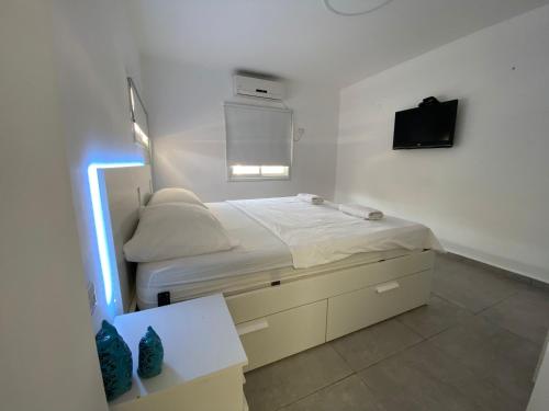 尼夫佐哈Romi's suite by LOREN VILLAGE的卧室配有一张床铺,墙上配有电视