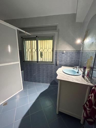 胡塞马Sfiha/Hoceima huis的蓝色瓷砖浴室设有水槽和窗户