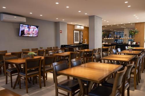 弗朗卡Morada Inn Hotel的餐厅设有木桌、椅子和平面电视。