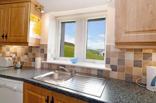 道宁斯Downings Coastguard Cottages - Type B-E的厨房设有水槽和窗户。