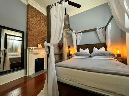 新奥尔良Luxury Historic Shotgun Home in Lower Garden District的一间卧室设有一张天蓬床和一个壁炉