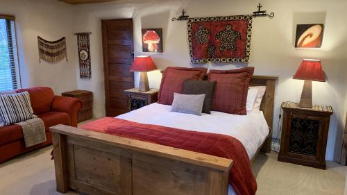 皇后镇Tussock Cottage的一间卧室配有一张大床和一张红色的沙发