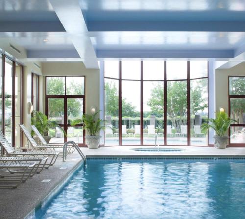 孟菲斯Memphis Vitality Hotel的游泳池,带椅子和窗户