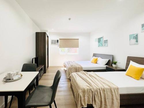 Punta EngañoFurnished Rentals at Mangrove Residences Mactan的酒店客房带两张床和一张桌子以及椅子。