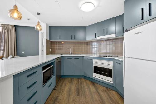 悉尼Chatswood Hub Self- Catering 815的厨房配有蓝色橱柜和白色家电