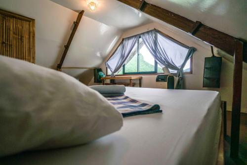 爱妮岛Bangka Hostels的一间卧室配有一张带枕头和窗户的床