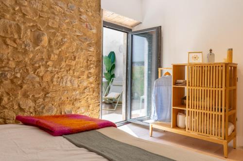 托罗埃利亚-德蒙特格里Empordanna, Apartamento con encanto en el corazón del Empordà的一间卧室设有石墙、一张床和一个窗户。