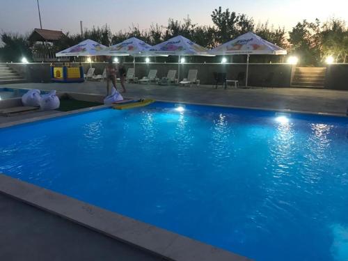 Hidişelul-de SusMARADA felix的夜间带遮阳伞的大型蓝色游泳池