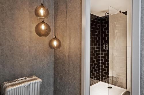 汉堡THE SCOTTY Hotel Hamburg的浴室设有2盏吊灯和淋浴。