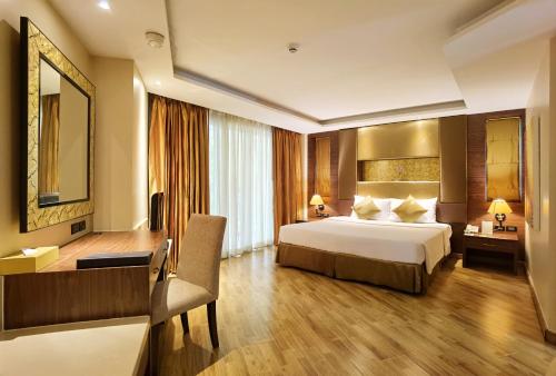 芭堤雅市中心Nova Gold Hotel Pattaya的配有一张床和一张书桌的酒店客房