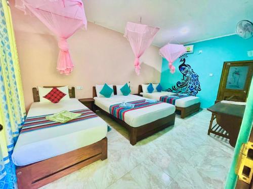 锡吉里亚Gangadiya Lodge的配有两张粉红色和蓝色墙壁的床铺