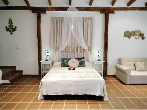 孔佩塔Casa Rural Las Adelfas的卧室配有白色的床和沙发