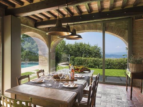 阿雷佐Ritzy Villa on a Wine Estate in Arezzo with Pool的一间设有桌子并享有游泳池景致的用餐室