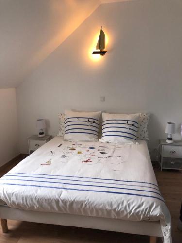 Bricqueville-sur-MerLe Bout du Monde的一张带两个枕头的白色床和墙上的一盏灯
