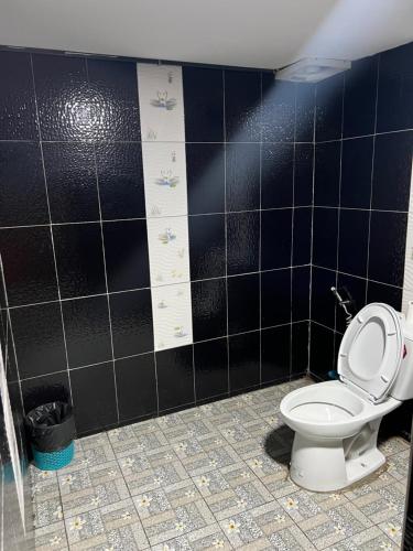 ครูไสวโฮมสเตย์的一间带卫生间的浴室和黑色瓷砖墙