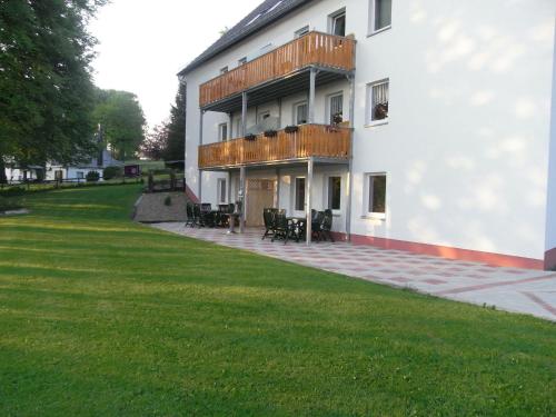 布尔格-罗伊兰德Comfy Holiday Home in Burg Reuland with Sauna Terrace BBQ的白色的建筑,有甲板和草地庭院