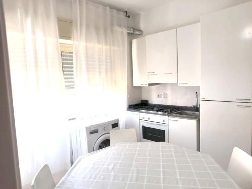 圣泰雷萨迪里瓦Pozzo Lazzaro Apartments的厨房配有白色橱柜和白色桌椅