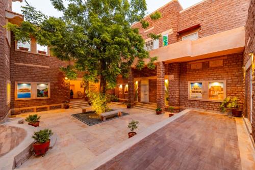 焦特布尔Tree Of Life Bhadrajun House, Jodhpur的一座空的庭院,里面有树和砖砌的建筑