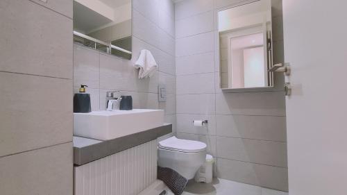帕拉利米尼STAY Mediterranean Waves Apartment的一间带水槽、卫生间和镜子的浴室