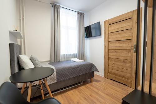 波兹南Apartamenty Słowackiego 16的一间卧室配有一张床、一张桌子和一个窗户。