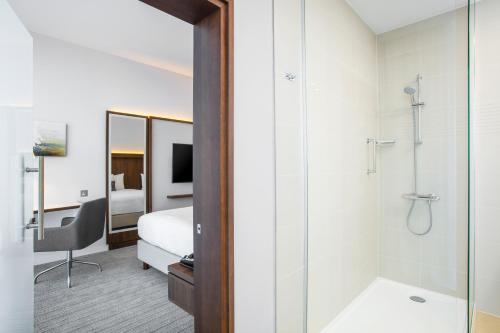 爱丁堡Courtyard by Marriott Edinburgh West的酒店客房设有淋浴和一间卧室。