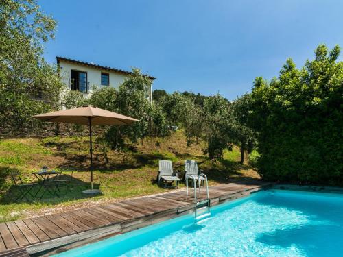UzzanoIdyllic Holiday Home in Pescia with Swimming Pool的一座房子旁的游泳池,配有两把椅子和一把遮阳伞