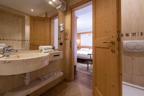 平佐洛Hotel Cristina的一间带水槽和镜子的浴室以及一张床