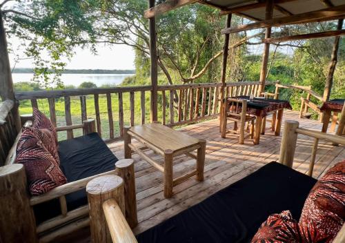 Murchison Falls National ParkMurchison Giraffe Camp的木制甲板上配有桌椅