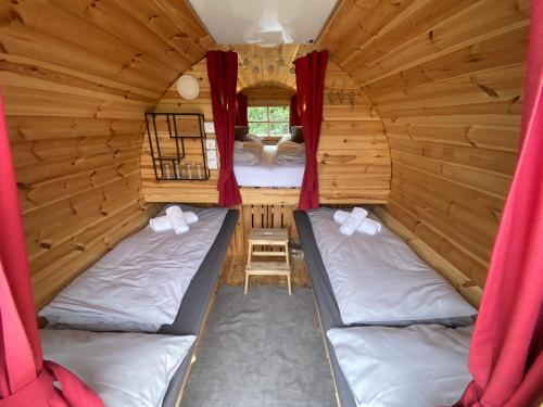 FriedersbachAndrella Auszeithof - Schlaferlebnis im Holzfass的一间设有两张床铺的小屋,配有红色窗帘