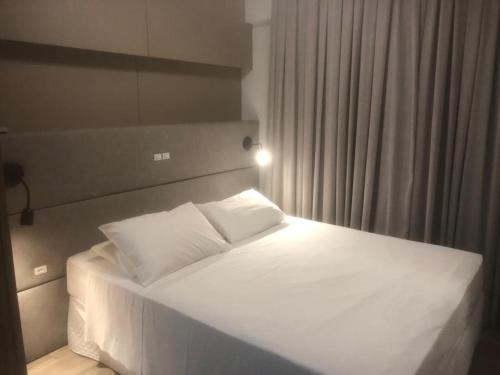 巴拉奈里奥-坎布里乌Apart-hotel Central com Spa的卧室内的一张带白色床单和枕头的床