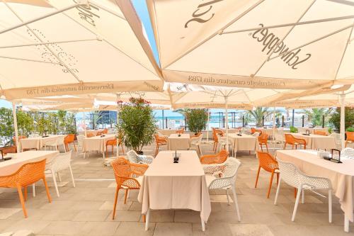 马马亚马里布酒店的一间设有白色桌椅和遮阳伞的餐厅