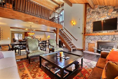 帕克城RP128 Ski-IN OUT Silver Lake的客厅设有石制壁炉和桌子。
