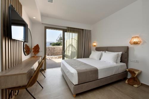 阿达玛斯Anais Milos Suites的一间卧室配有一张床、一张书桌和一台电视