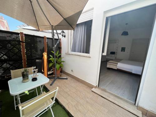 安齐奥DMC - Alloggio Turistico的阳台的天井配有桌子和遮阳伞。