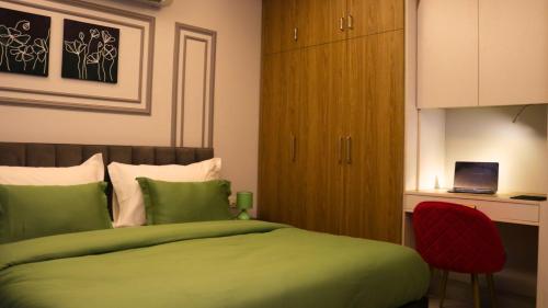 古尔冈AVA Hotels and Corporate Suites的一间卧室配有绿色的床和红色椅子