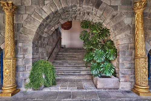 库斯科Palacio del Inka, a Luxury Collection Hotel, Cusco的建筑中带有楼梯和植物的拱门