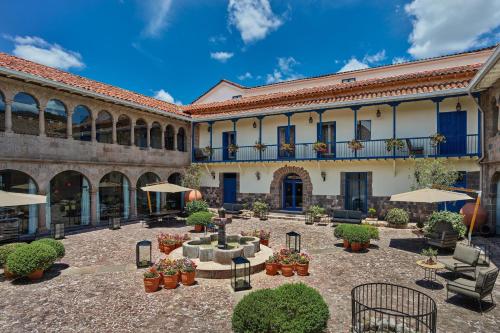 库斯科Palacio del Inka, a Luxury Collection Hotel, Cusco的一座带桌子和遮阳伞的庭院