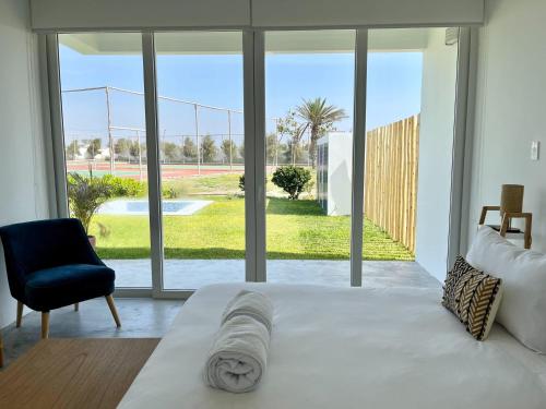 帕拉卡斯Ocean Breeze 5BR in Paracas Beach的一间卧室配有一张床、一把椅子和一个大窗户