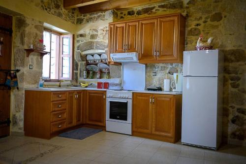 KrousónTraditional Stone Mezonete的厨房配有白色冰箱和木制橱柜。