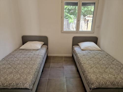马尔格里特Villa Marguerittes的两张床位于带窗户的房间内