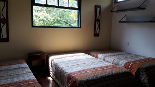 瓜皮米林Guapimirim Casa de Campo的带窗户的客房内的两张床