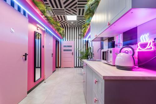 弗罗茨瓦夫VICE CITY Hostel的厨房设有粉红色的墙壁和带电器的台面